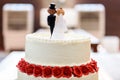 White wedding cake with bride and groom figurines on top Royalty Free Stock Photo